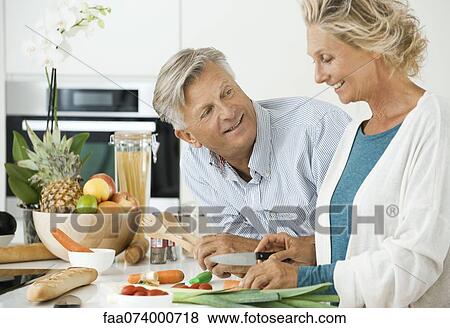 Mature couple preparing food together in kitchen View Large Photo Image Stock Photo - Mature couple preparing food together in kitchen. Fotosearch
