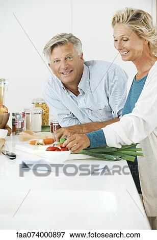 Mature couple preparing food together in kitchen View Large Photo Image Stock Photo - Mature couple preparing food together in kitchen. Fotosearch