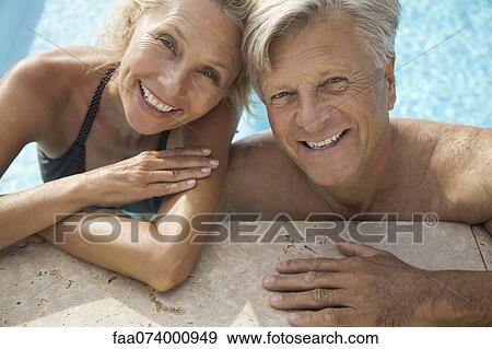 Stock Photo - Mature couple relaxing together in pool, portrait. Fotosearch