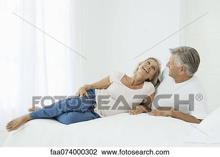 Mature couple relaxing together on bed View Large Photo Image Stock Image - Mature couple relaxing together on bed. Fotosearch