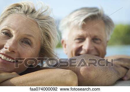 Mature couple resting their heads on side of pool, portrait View Large Photo Image Stock Image - Mature couple resting their heads on side of pool, portrait. Fotosearch