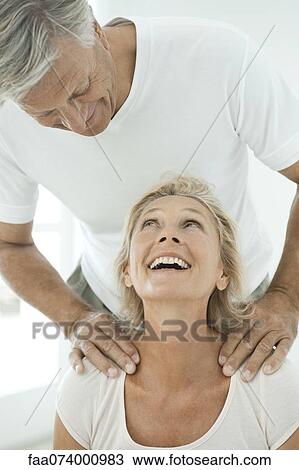 Mature couple smiling at each other as man massages woman's shoulders View Large Photo Image Stock Image - Mature couple smiling at each other as man massages woman's shoulders. Fotosearch