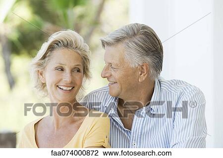 Stock Image - Mature couple smiling at each other outdoors. Fotosearch