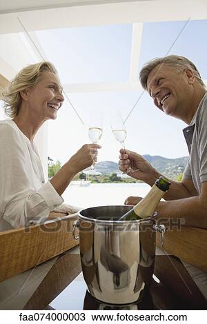 Stock Image - Mature couple toasting with champagne. Fotosearch