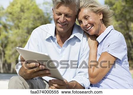 Mature couple using digital tablet outdoors View Large Photo Image Stock Photography - Mature couple using digital tablet outdoors. Fotosearch