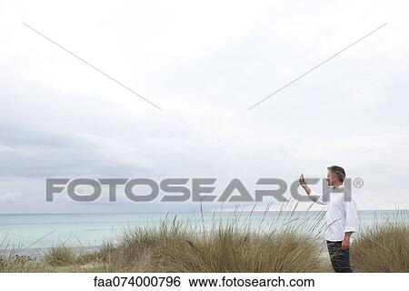 Mature man photographing scenery using cell phone View Large Photo Image Stock Photograph - Mature man photographing scenery using cell phone. Fotosearch