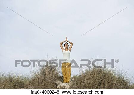 Stock Photograph - Mature woman doing sun salutation yoga pose. Fotosearch