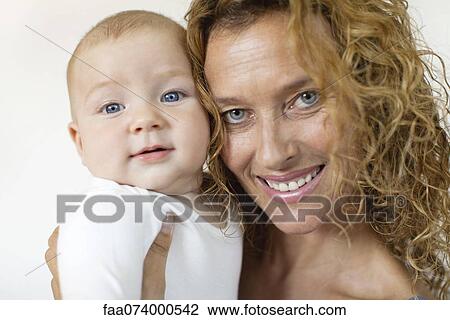 Stock Image - Mature woman holding baby, portrait. Fotosearch