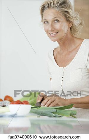 Stock Image - Mature woman preparing healthy food, portrait. Fotosearch