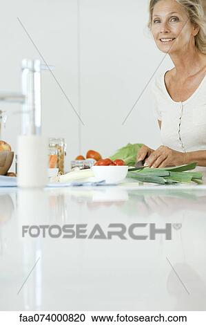 Mature woman preparing healthy meal, smiling at camera View Large Photo Image Stock Image - Mature woman preparing healthy meal, smiling at camera. Fotosearch