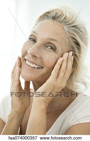 Mature woman touching cheeks, smiling, portrait View Large Photo Image Stock Photo - Mature woman touching cheeks, smiling, portrait. Fotosearch