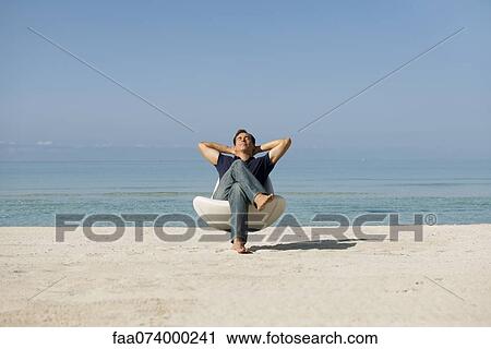 Mid-adult man relaxing in armchair on beach with eyes closed View Large Photo Image Stock Image - Mid-adult man relaxing in armchair on beach with eyes closed. Fotosearch