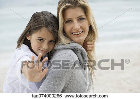 Stock Photograph - Mother carrying daughter, daughter doing stop gesture at camera, portrait. Fotosearch