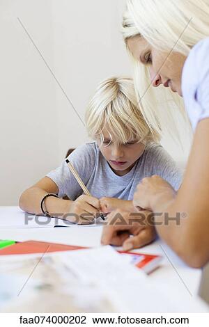 Stock Image - Mother helping son with homework. Fotosearch