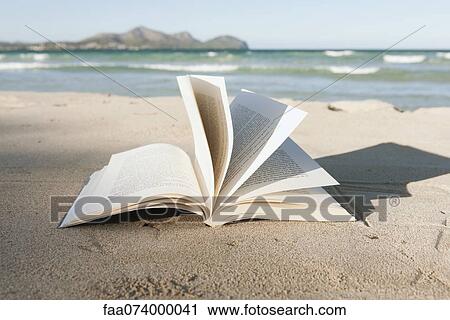 Stock Image - Open book on beach. Fotosearch