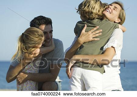 Parents embracing children at the beach View Large Photo Image Picture - Parents embracing children at the beach. Fotosearch