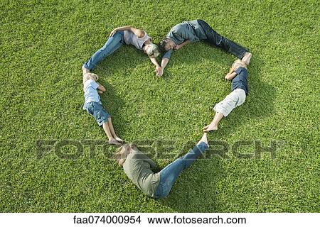 Picture - People lying on grass positioned in shape of heart. Fotosearch