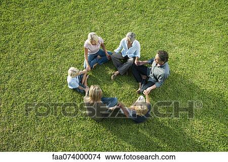 People sitting in circle on grass holding hands View Large Photo Image Picture - People sitting in circle on grass holding hands. Fotosearch
