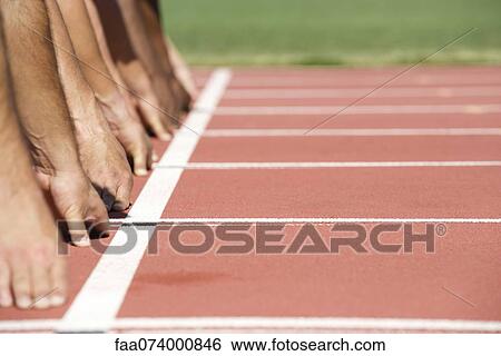 Stock Photograph - Runners crouched at starting line, cropped. Fotosearch