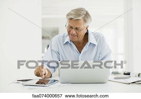 Senior man using digital tablet and laptop computer View Large Photo Image Stock Photo - Senior man using digital tablet and laptop computer. Fotosearch