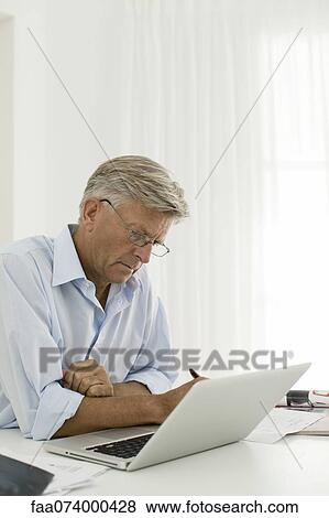 Senior man working on laptop computer at home View Large Photo Image Stock Photo - Senior man working on laptop computer at home. Fotosearch