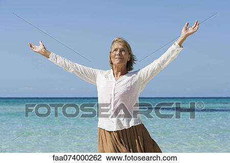 Senior woman by sea with arms outstretched View Large Photo Image Stock Image - Senior woman by sea with arms outstretched. Fotosearch