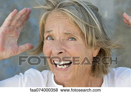 Stock Photo - Senior woman with hands raised and look of astonishment. Fotosearch