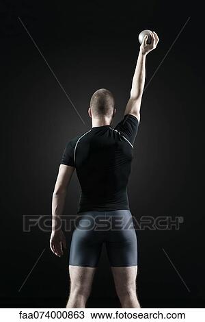 Stock Image - Shot putter holding shot, rear view. Fotosearch