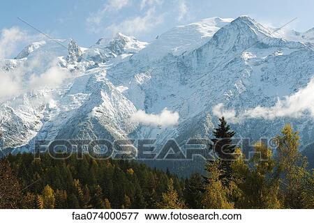 Stock Photo - Snow-covered mountain range and forest in autumn hues. Fotosearch