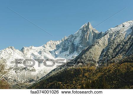 Snow-covered mountain range and forest in autumn hues View Large Photo Image Stock Photograph - Snow-covered mountain range and forest in autumn hues. Fotosearch