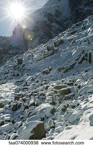 Stock Photo - Sun shining over snowy mountain. Fotosearch