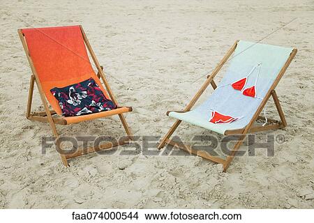Picture - Swimsuits left on lounge chairs at the beach. Fotosearch
