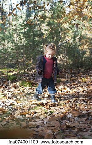 Stock Photo - Toddler girl walking in autumn leaves. Fotosearch