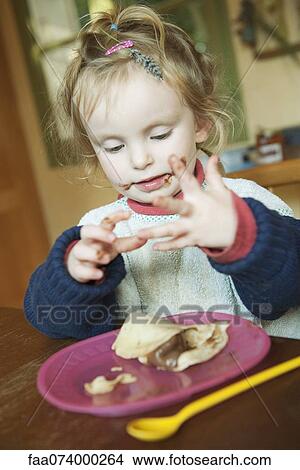 Picture - Toddler playing with hands while eating snack. Fotosearch