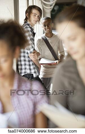 Stock Photograph - University students discussing homework outdoors, focus on background. Fotosearch