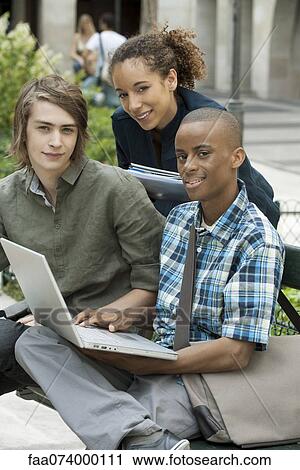 Stock Image - University students studying on campus with laptop computer, portrait. Fotosearch