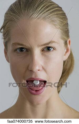 Stock Photography - Vitamin pill on young woman's tongue. Fotosearch