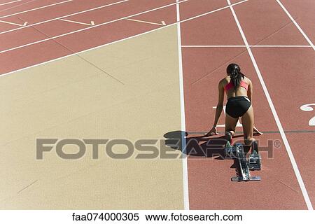 Woman crouched in starting position on running track, rear view View Large Photo Image Stock Photography - Woman crouched in starting position on running track, rear view. Fotosearch