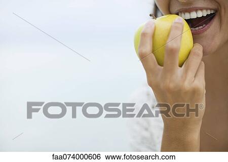 Stock Photograph - Woman eating apple, cropped. Fotosearch
