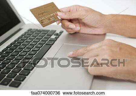 Woman holding credit card while using laptop computer, cropped View Large Photo Image Stock Photograph - Woman holding credit card while using laptop computer, cropped. Fotosearch