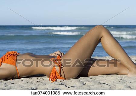 Woman in bikini sunbathing on beach, mid section View Large Photo Image Stock Photography - Woman in bikini sunbathing on beach, mid section. Fotosearch
