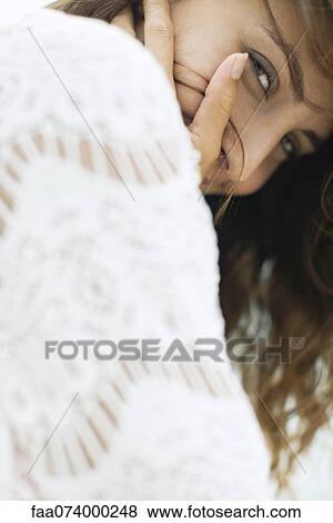 Woman looking over shoulder at camera, hand covering mouth View Large Photo Image Stock Photo - Woman looking over shoulder at camera, hand covering mouth. Fotosearch