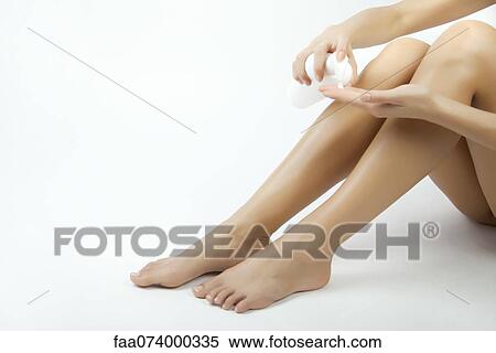 Stock Photography - Woman moisturizing legs, cropped. Fotosearch