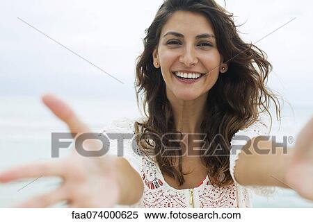 Stock Photography - Woman reaching arms toward camera, smiling. Fotosearch