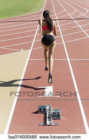 Stock Photo - Woman running on track, rear view. Fotosearch