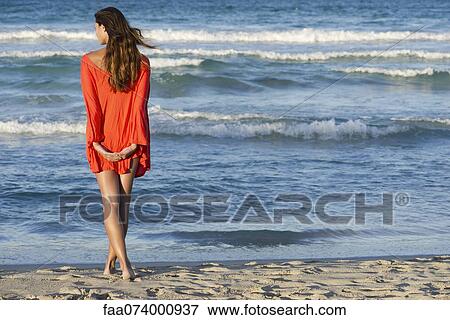 Woman standing on beach looking at ocean view, rear view View Large Photo Image Stock Photo - Woman standing on beach looking at ocean view, rear view. Fotosearch