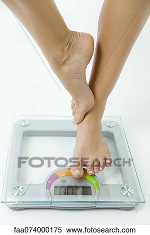 Woman standing on one leg on bathroom scale, low section View Large Photo Image Stock Photography - Woman standing on one leg on bathroom scale, low section. Fotosearch