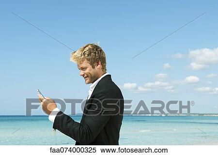 Young businessman using cell phone by ocean, side view View Large Photo Image Stock Photography - Young businessman using cell phone by ocean, side view. Fotosearch