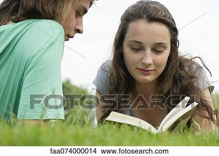 Picture - Young couple reading book together outdoors. Fotosearch