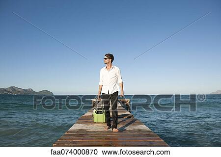 Young man pulling luggage and walking on pier View Large Photo Image Stock Image - Young man pulling luggage and walking on pier. Fotosearch